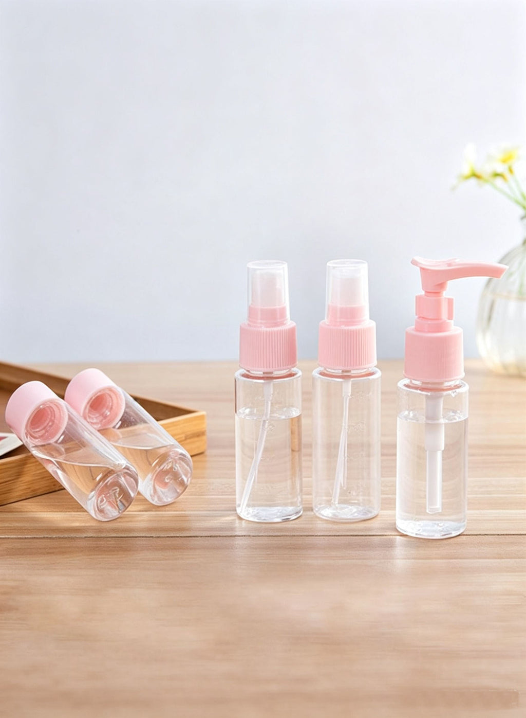 Pink travel bottles on wooden tray