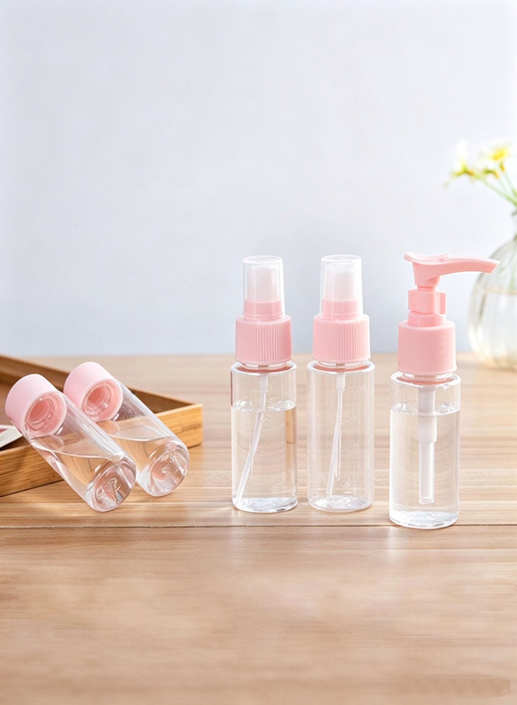 Pink travel bottles on wooden tray